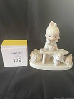 Front view of the Precious Moments Jonathan David figurine showing the child seated on a bench with three lambs, in primarily white porcelain.