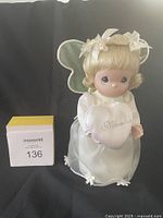 November angel doll holding a heart-shaped pillow embroidered with 'November' shown against neutral background.