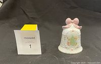 Front view of the Precious Moments Christmas bell figurine with pastel decorations and pink bow on top.
