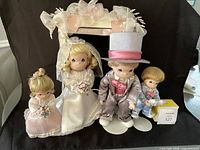 Photo showing four Precious Moments bridal party porcelain figurines around a decorative arch.