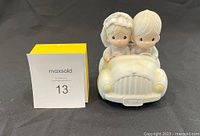 Front view of the Precious Moments ceramic figurine showing a girl and boy in a car with the 'IN L09' license plate.