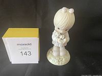 Front view of the Easter Precious Moments figurine with child holding a cat and maxsold lot number.
