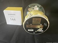 Bottom of music box showing Precious Moments branding, music box label indicating Joy To The World, and wind-up key.