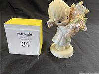 Photo of the figurine standing showing front and side details with yellow and white maxsold cube beside for scale.