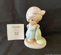 Front view of the Precious Moments figurine showing the girl with a bonnet holding a vacuum cleaner on a textured oval base.