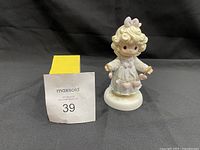 Front view of the Precious Moments figurine showing the girl in white dress holding pink hearts.