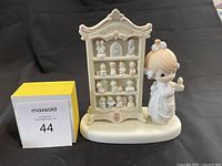 Front view of the Precious Moments commemorative figurine showing a girl with a bird and detailed miniature cabinet display labeled 'My Collection'.