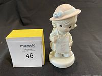 Front view of the Precious Moments 1995 figurine holding a 'Follow your heart' sign next to a yellow MaxSold lot number block