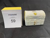 Photo showing the Precious Moments November 1995 porcelain chest figurine with closed lid, featuring gold heart and key details.