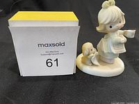 Front view of Precious Moments figurine showing the girl with a watering can and dog on oval base.