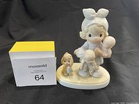Front view of Precious Moments figurine showing girl with two babies and a small dog on base alongside measurement box.