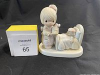 Front angle of Precious Moments 'Make Me A Blessing' figurine showing child with honey jar and sleeping figure on bed.