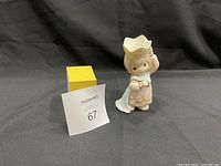 Front view of Precious Moments figurine with crown and cape, posed holding a heart.