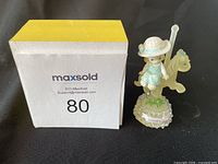 Figurine including the girl in blue dress with carousel horse and yellow and white box with lot number 80.
