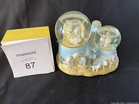 Photo of the Precious Moments 'Away In A Manger' music box figurine with Nativity scene and seller's maxsold lot number.