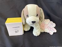 Front view of a plush beagle puppy sitting with attached Precious Moments tags, against a black background.