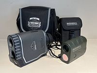 Two Bushnell golf rangefinders, Pro 1600 and Yardage Pro, with their black carrying cases on a white background.