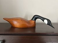 Left side angle of the Canada Goose carved wooden decoy showing the smooth natural wood body with black painted neck and head with white facial markings.