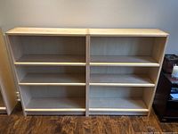 Front view of two IKEA bookshelves in natural maple veneer with shelves inside and tops visible.