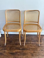 Front view of both chairs side by side on wood floor against wall