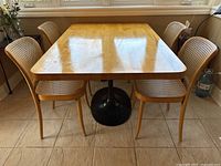 Front view of the table showing maple top and black pedestal base