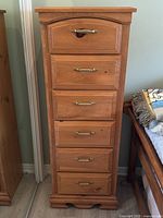 Front view of the pine chest showing all six drawers with brass-tone handles and the gently arched top drawer front.