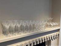 Shelf display of assorted Stuart cut crystal stemware arranged in rows including wine and champagne glasses.