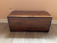 Full front view of vintage rustic wooden storage chest showing wood grain and metal corner reinforcements.