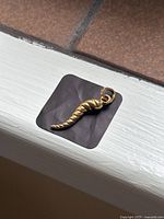 Pendant laid flat on a white window sill with tile background, full frontal view