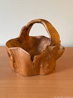 Front view of carved wooden basket showing handle and organic shape.