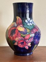 Front view of vase on wooden surface, showing full orchid decoration