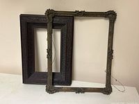Both antique wooden picture frames shown side-by-side against a neutral background, highlighting their differing styles, materials, and condition.