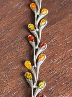 Close-up showing branch-like sterling silver design with teardrop amber stones in yellow, orange, and honey colors