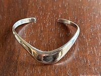 Front view of the sterling silver bracelet showing the V-shaped wider central section and polished surface.