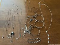 Overview of entire lot showing necklaces, bracelets, bangles and rings on wooden surface