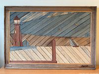 Full view of rectangular wooden wall art with lighthouse, sailboat, sky, and birds in natural and painted wood colors, signed by DeGroot in lower right corner.