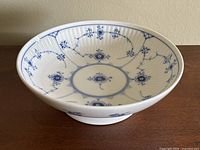 Blue and white Royal Copenhagen porcelain pedestal bowl shown from angled top view highlighting floral interior design and ribbed texture.