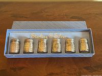 Photo of the set of six sterling silver salt and pepper shakers arranged inside original blue box labeled 'Sterling Silver'