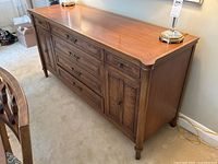 Full front-left angle view of the walnut sideboard showing top surface, drawers and left cabinet door.