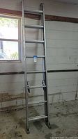 Full view of the Werner aluminum extension ladder extended and resting against wall.