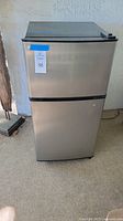 Front view of stainless steel Anukis compact refrigerator/freezer.