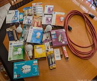 Photo showing assortment of lightbulbs and coiled outdoor extension cord on table