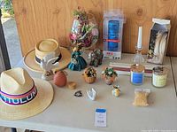 Full lot view showing hats, candles, small decorative figurines including bird, flowers, an elephant, and a boxed blue 808 HEX SL Bluetooth speaker.