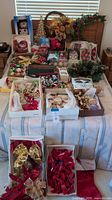 Photo showing a large assortment of Christmas decorations including ornaments, bows, garlands, and a fiber optic snowman on a table with a window behind.