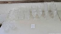 Wide view of all crystal glassware showing tumblers, wine glasses, champagne flutes, and highball glasses on table.