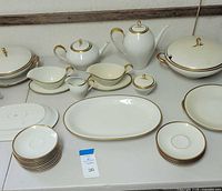Eschenbach German china set including coffee pot, tea pot, tureen, gravy boats, sugar and creamer, plates, and saucers on a table.
