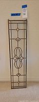 Full view photo of the long narrow leaded glass panel positioned upright against a wall showing the entire design and structure.
