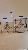 Two clear leaded glass panels side by side on floor, showing their overall sizes and designs