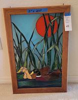 Full view of the stained glass panel in the wooden frame showing the two ducks, green reeds, and large orange sun.