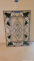 Full view of the hand crafted stained glass panel showing the vine pattern, white flowers, and green leaves in a rectangular panel.